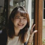 Smiling woman in café doorway, adding warmth and hospitality to a modern coffee shop.